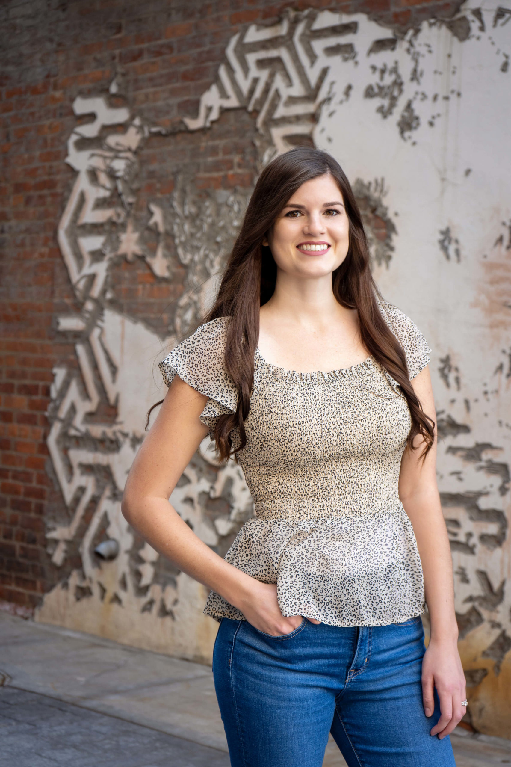 Jaclyn Pfingsten smiles for the camera as she poses in front of a wall. She is an online therapist in Michigan can offer support with online therapy in California and other services. Contact a young adult therapist in West Bloomfield, MI to learn more today! 94118 | 48322 | 48323